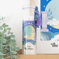 Decorative candle with moon design packaging on a shelf with a plant in the background