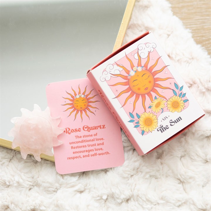 Two pink boxes with sun designs and text on a fluffy white surface