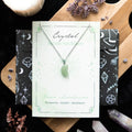 Crystal moon necklace on a branded card with decorative elements on a wooden surface.