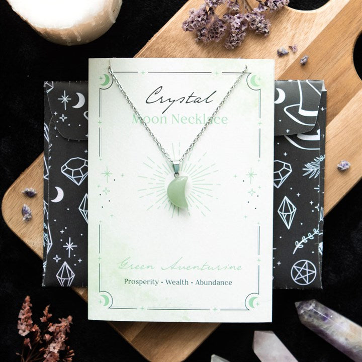 Crystal moon necklace on a branded card with decorative elements on a wooden surface.
