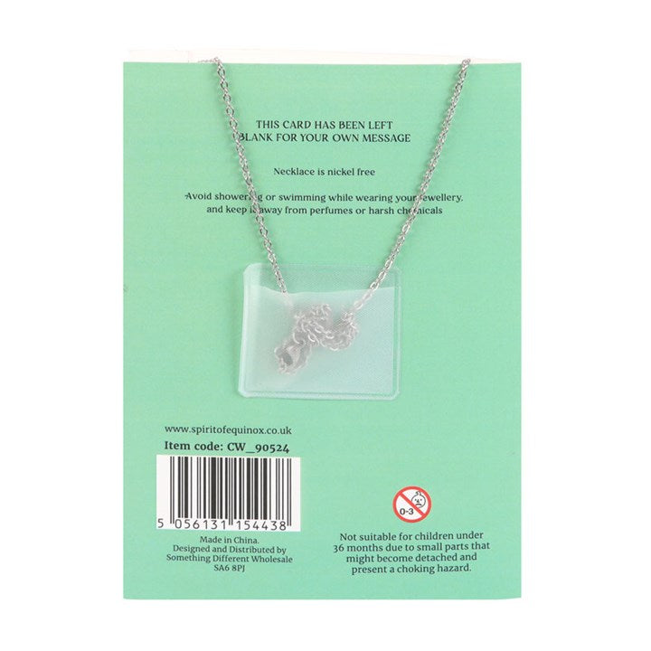 Necklace with a heart and key pendant on a green card with product information.