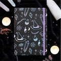 Notebook with mystical design on a dark background with candles and crystals