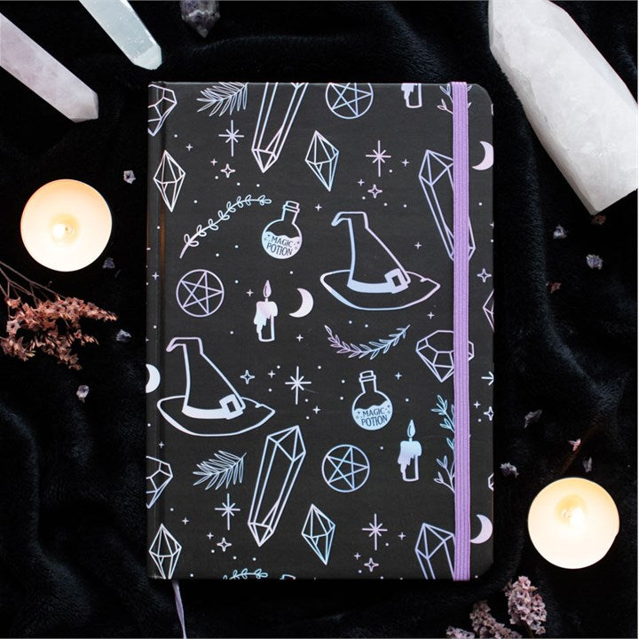 Notebook with mystical design on a dark background with candles and crystals