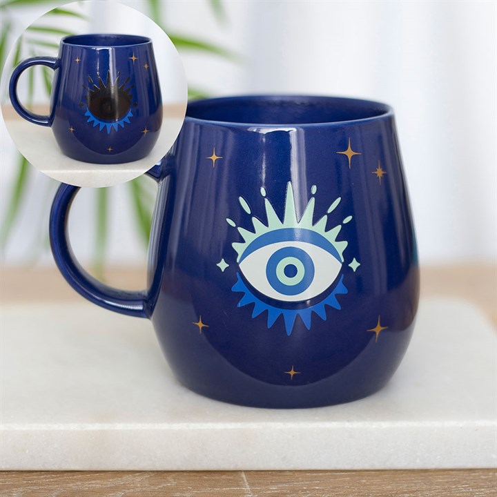 Blue mug with eye design on a white surface