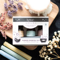 Box of blended essential oils with flowers and candles on a dark surface