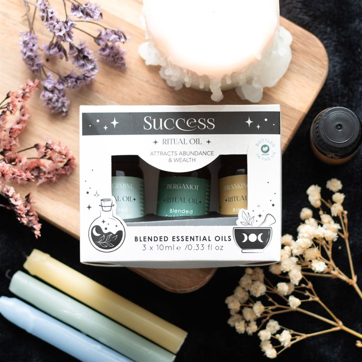 Blended essential oils set with candles and flowers on a dark surface