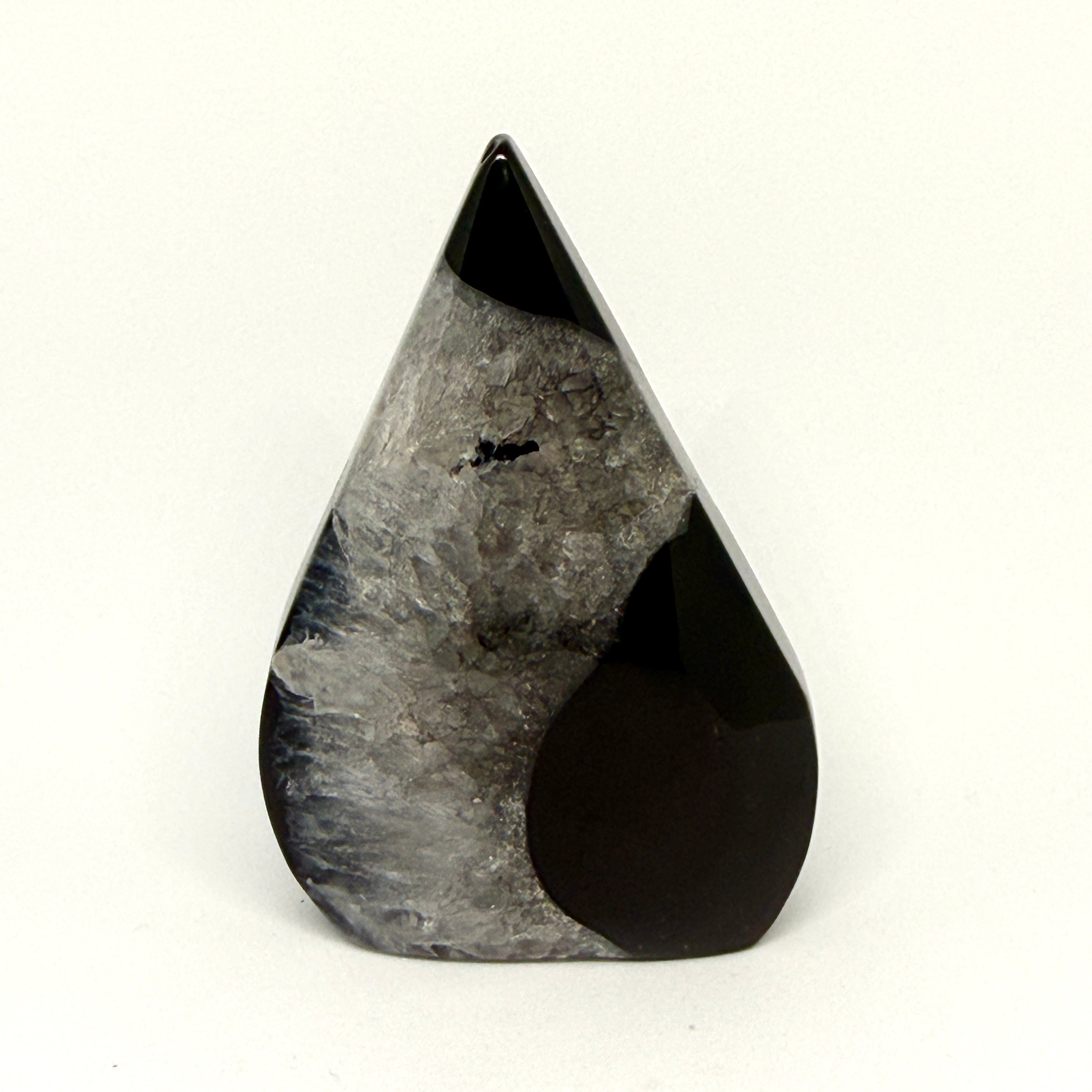 Teardrop-shaped black and gray stone sculpture on a white background