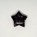 Star-shaped purple stone with a small gold chain on a white background