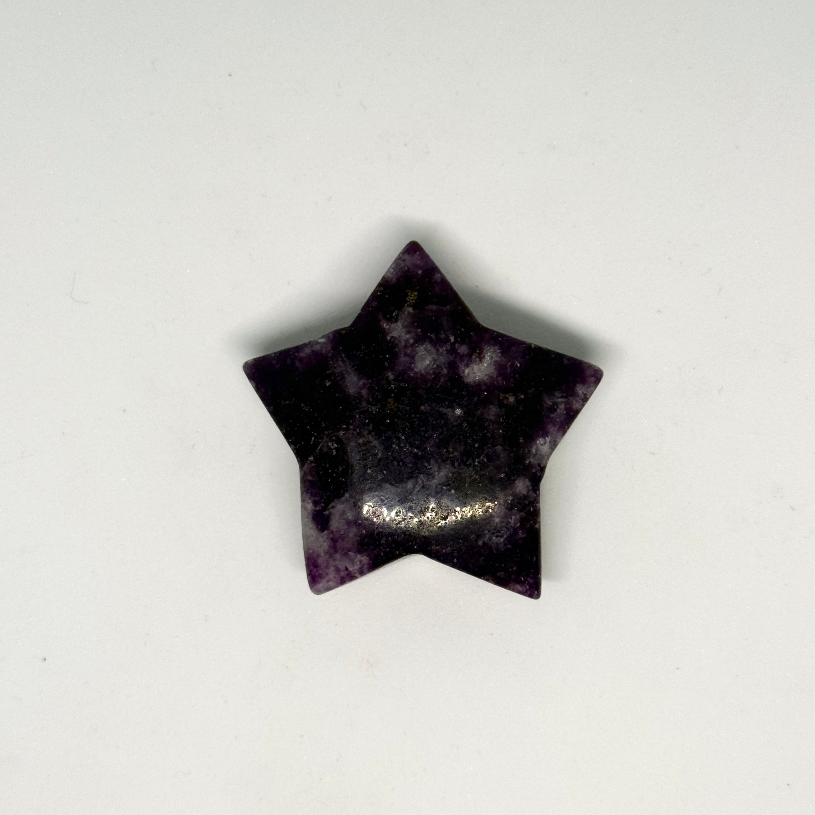 Star-shaped purple stone with a small gold chain on a white background