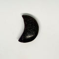 Black stone in the shape of a crescent moon on a white background