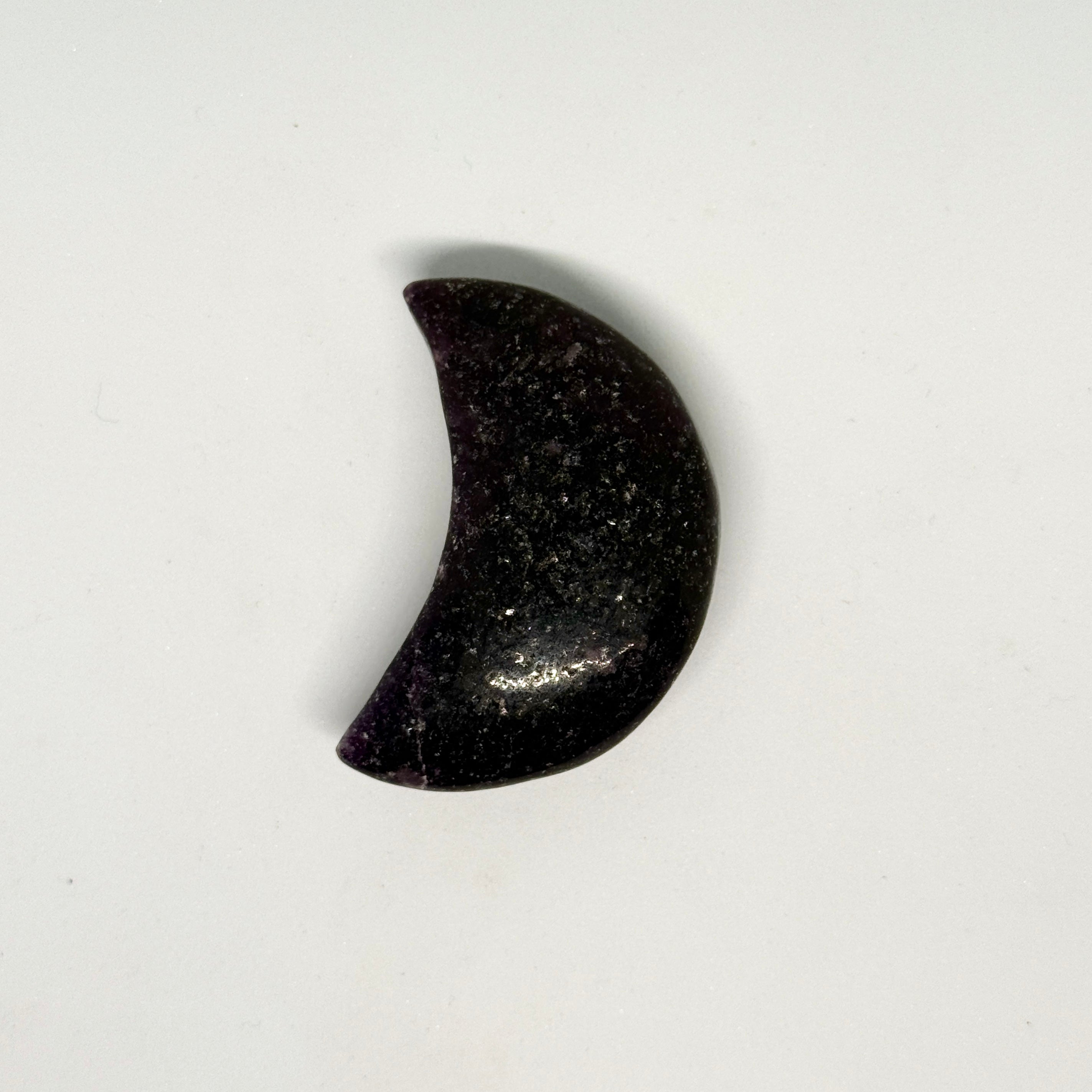Black stone in the shape of a crescent moon on a white background