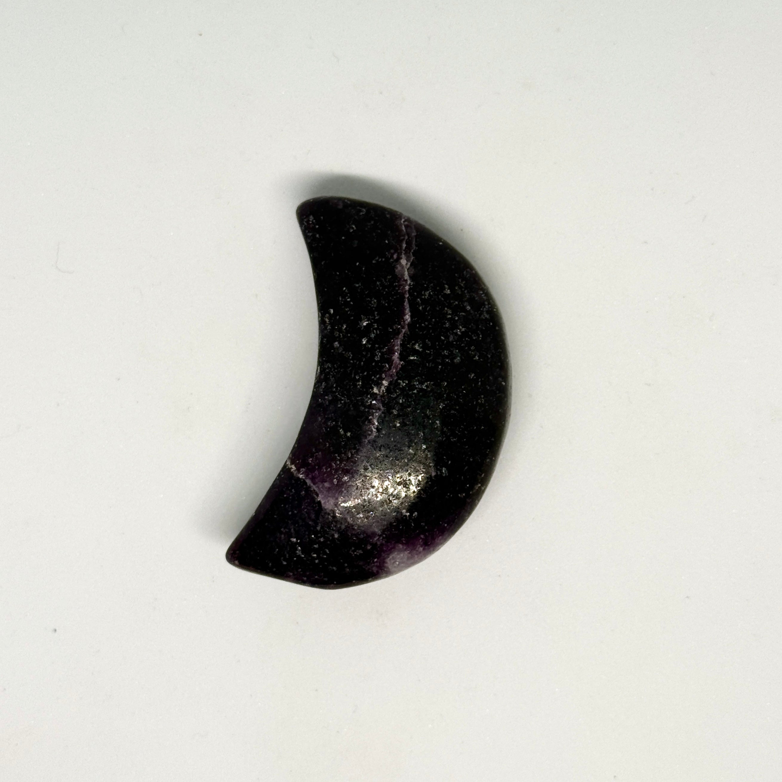 Black stone in the shape of a crescent moon on a white background