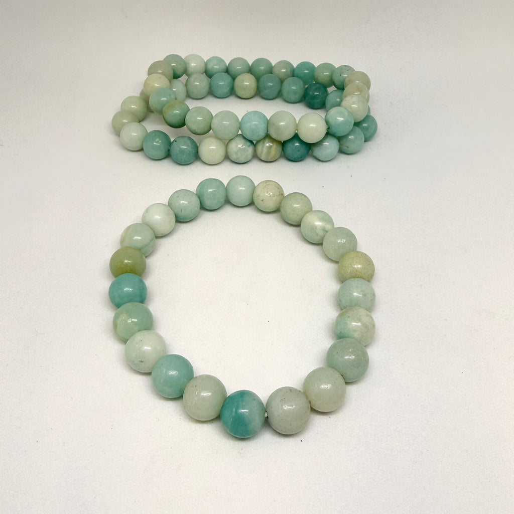 Two green and white beaded bracelets on a white background