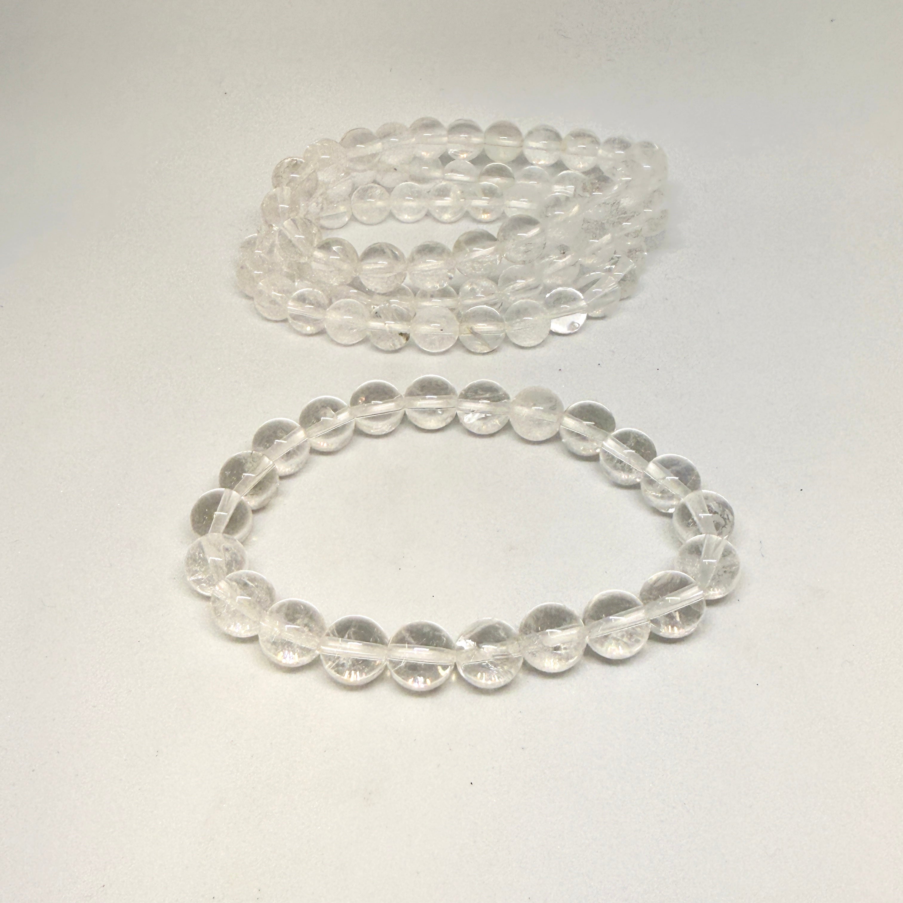 Two clear beaded bracelets on a light gray background