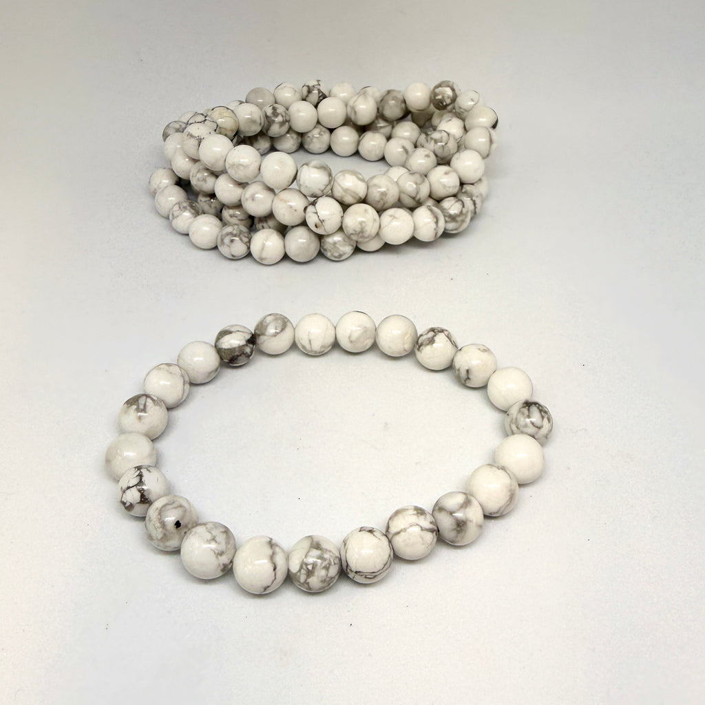 Two white beaded bracelets on a light gray background