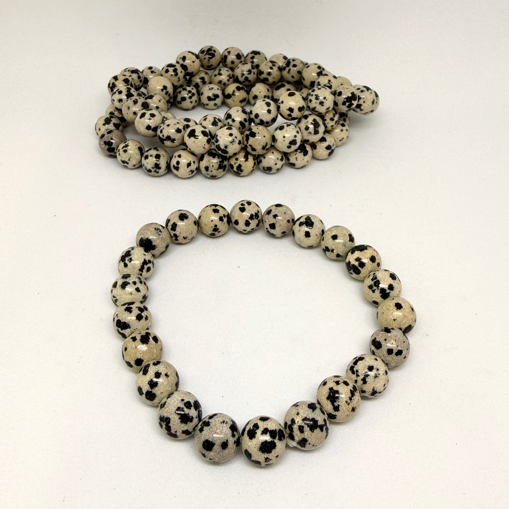 Two bracelets made of white beads with black spots on a white background