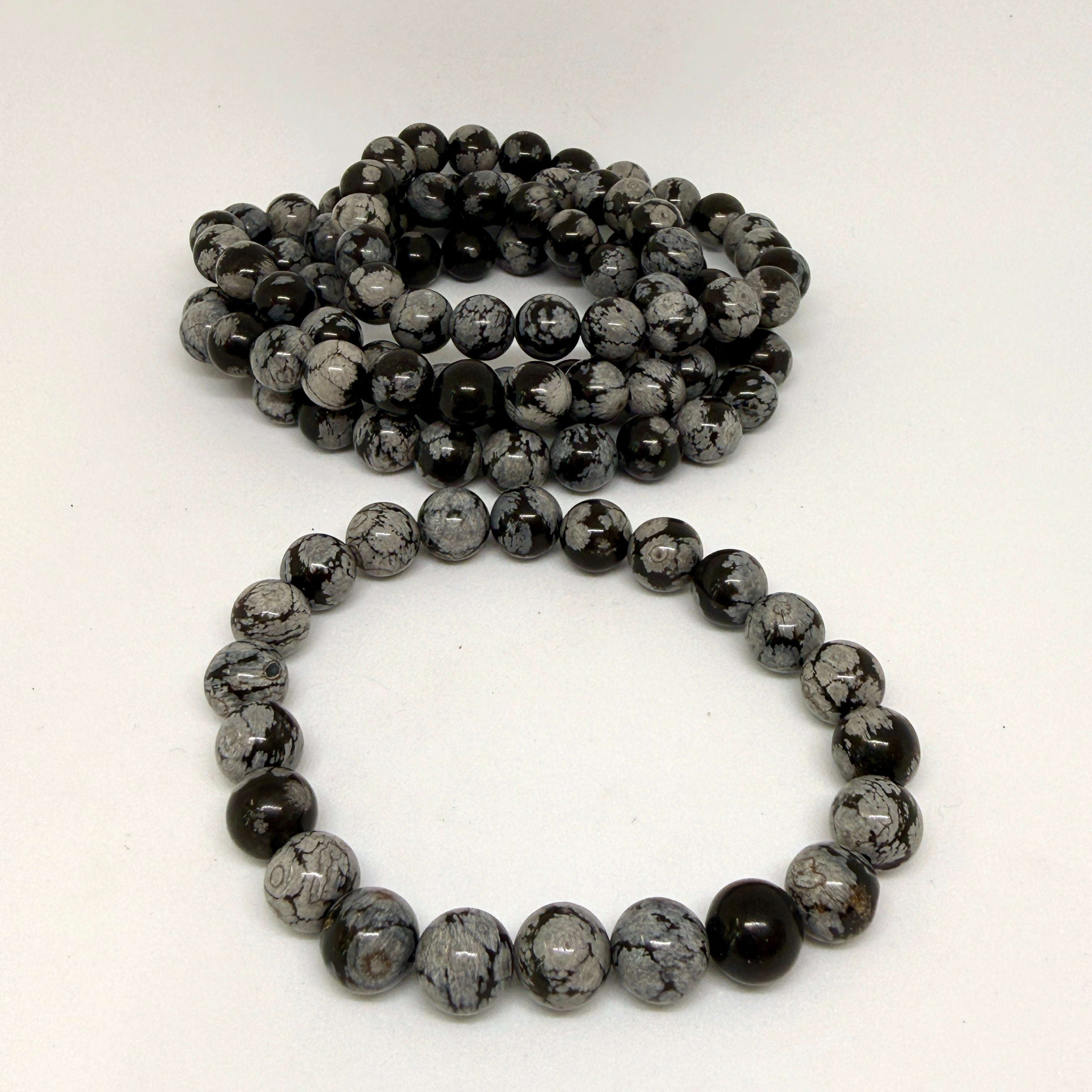 Two black and gray beaded bracelets on a white background