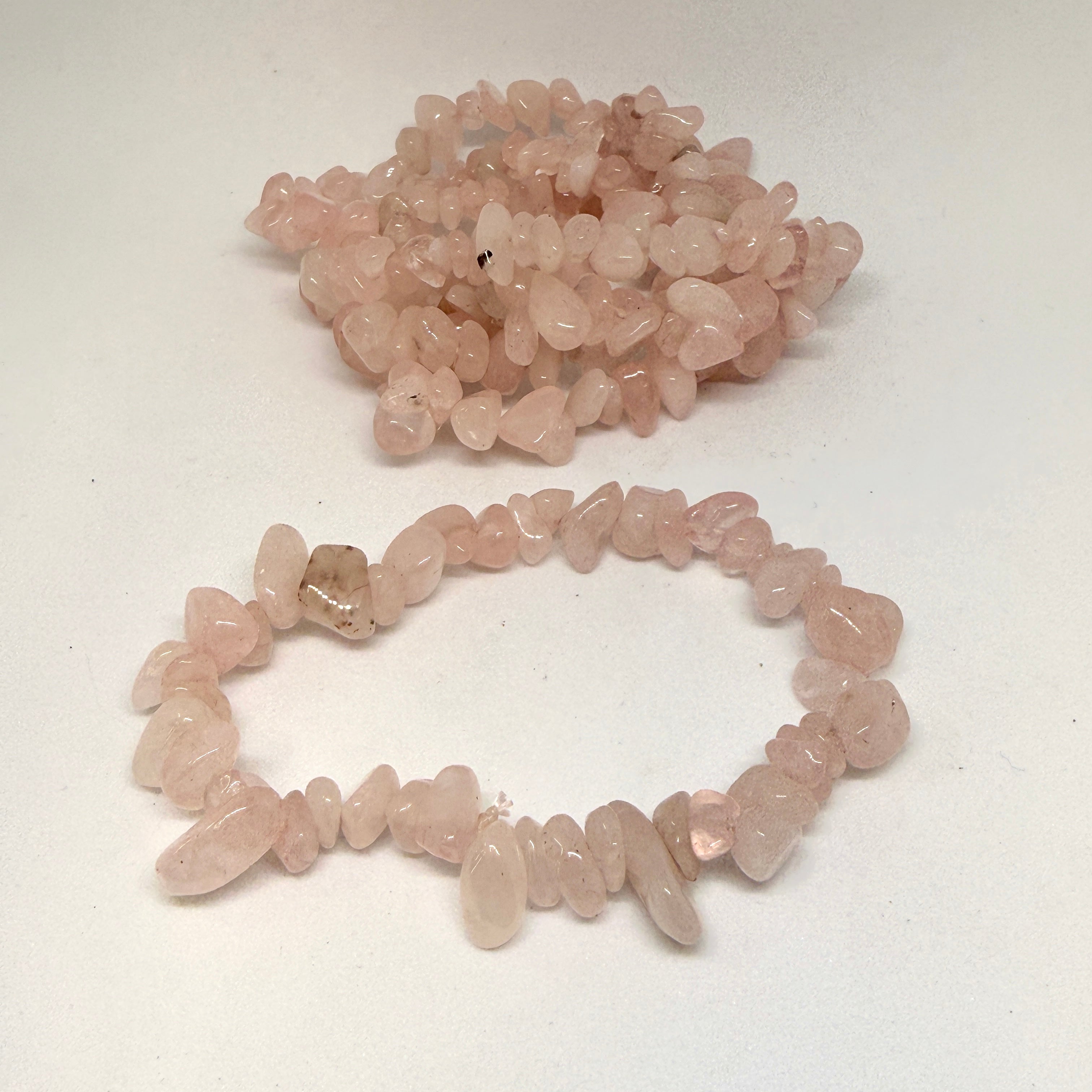 Bracelet and bracelet made of rose quartz chips on a white background