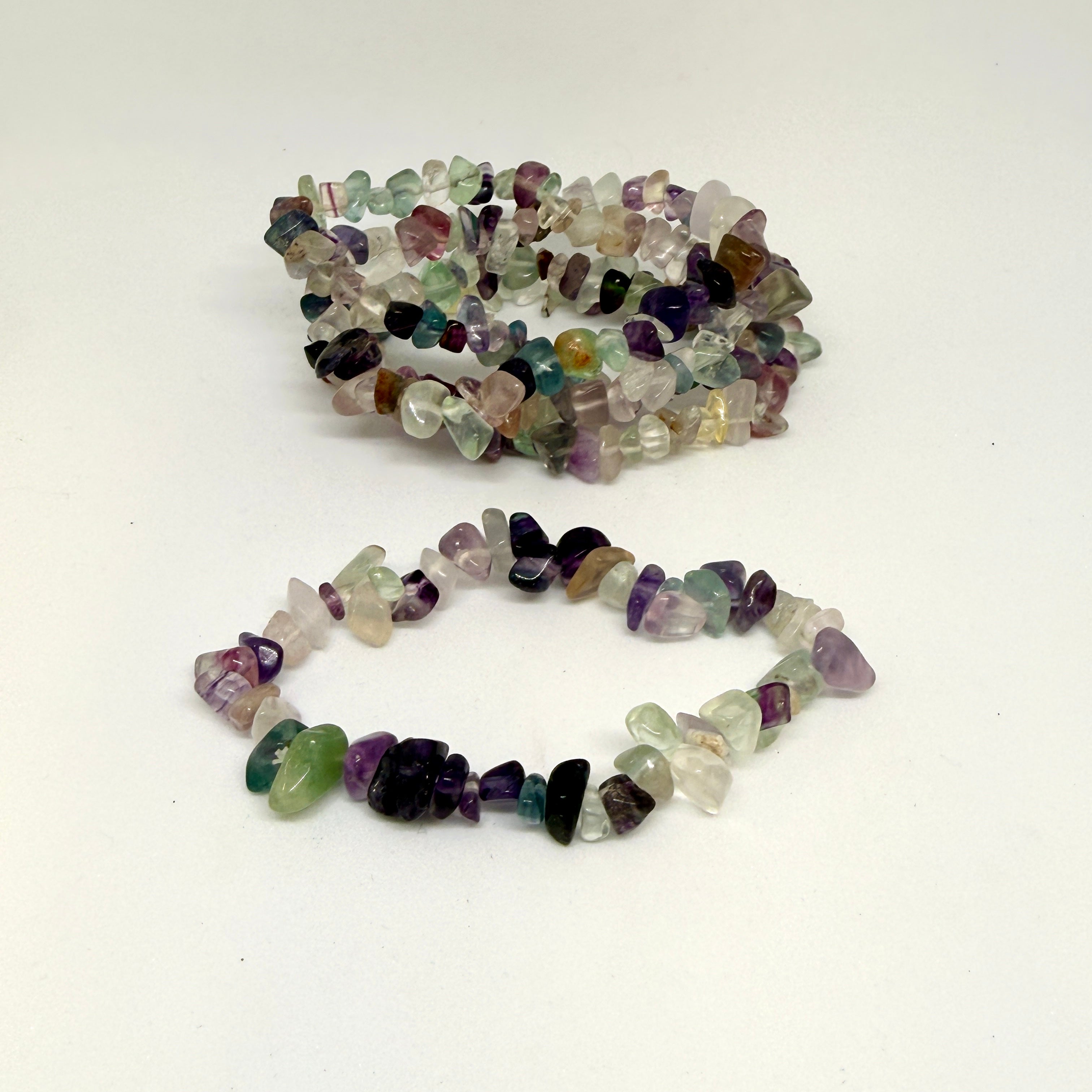 Multicolored gemstone chip bracelets on a white background