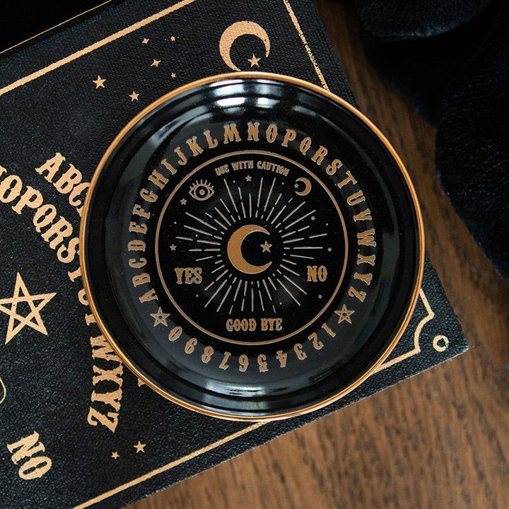 Decorative black and gold circular object with symbols on a wooden surface