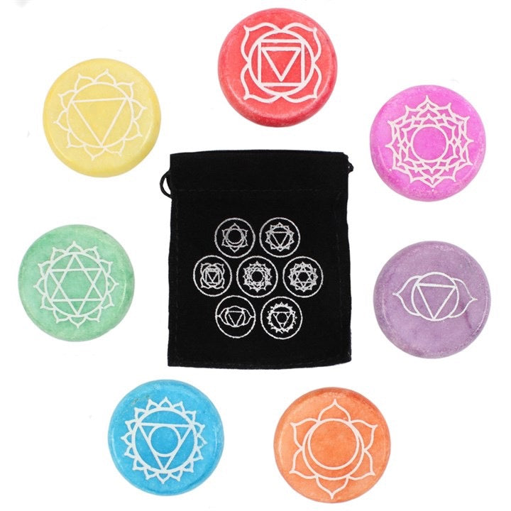 Set of colorful chakra stones with a black drawstring bag featuring similar symbols on a white background.