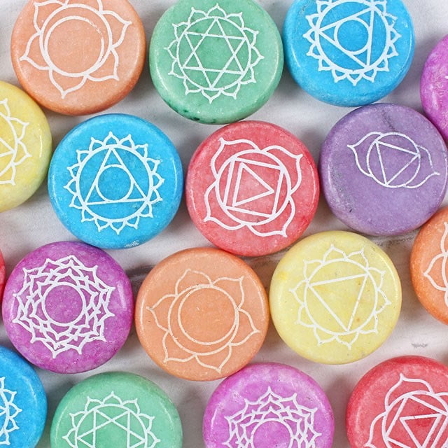 Colorful stones with white geometric symbols on a textured surface