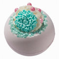 Bath bomb with a turquoise flower and pink beads on a white background