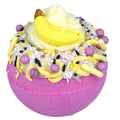 Decorative bath bomb with pink base, yellow and purple toppings on a white background
