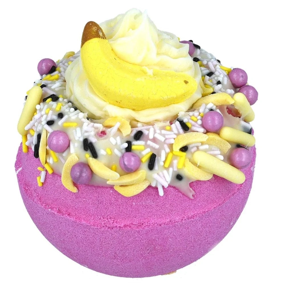 Decorative bath bomb with pink base, yellow and purple toppings on a white background