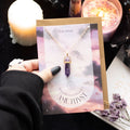 Amethyst necklace on a card with candles and flowers in the background