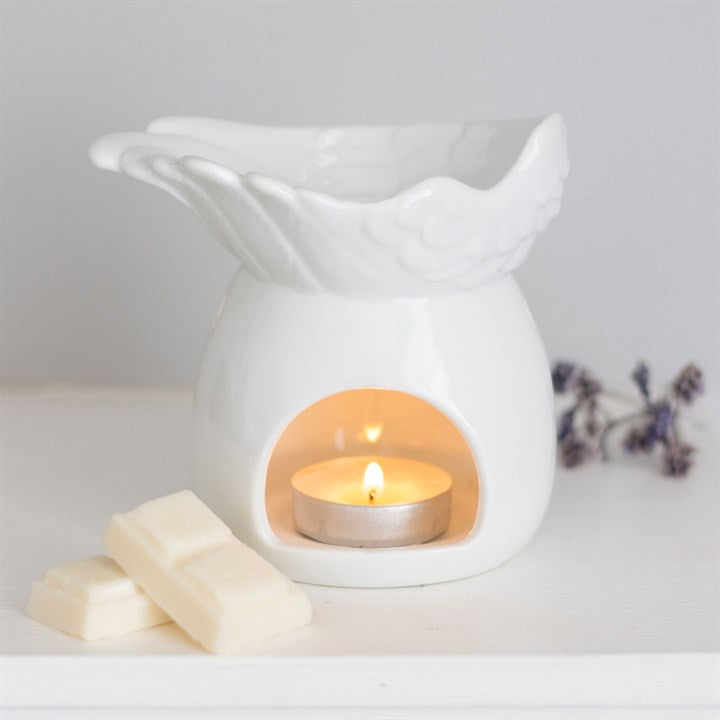 White ceramic warmer with a lit candle inside on a light gray background