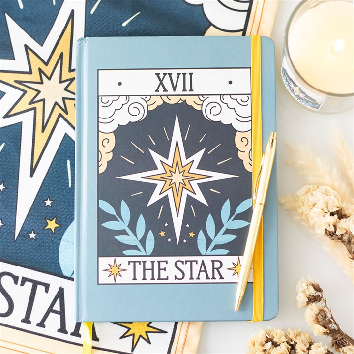 Notebook with 'The Star' tarot card design on a surface with star and card designs.
