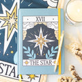 Notebook with 'The Star' tarot card design on a surface with star and card designs.