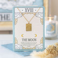 Gold necklace with a pendant on a card labeled 'The Moon' with decorative elements.