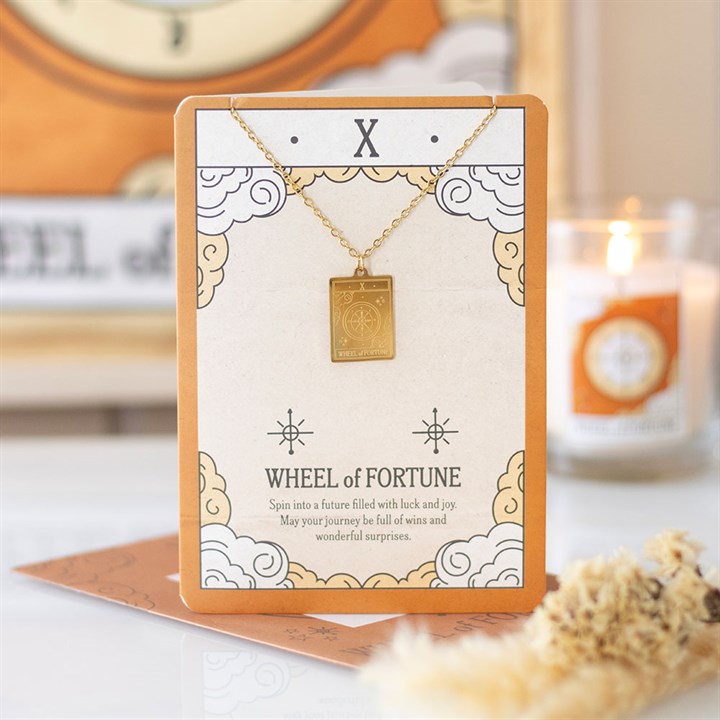 Gold necklace with 'Wheel of Fortune' pendant on a decorative card, with a blurred background.