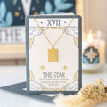 Gold necklace on a card with 'The Star' symbolism in a decorative setting