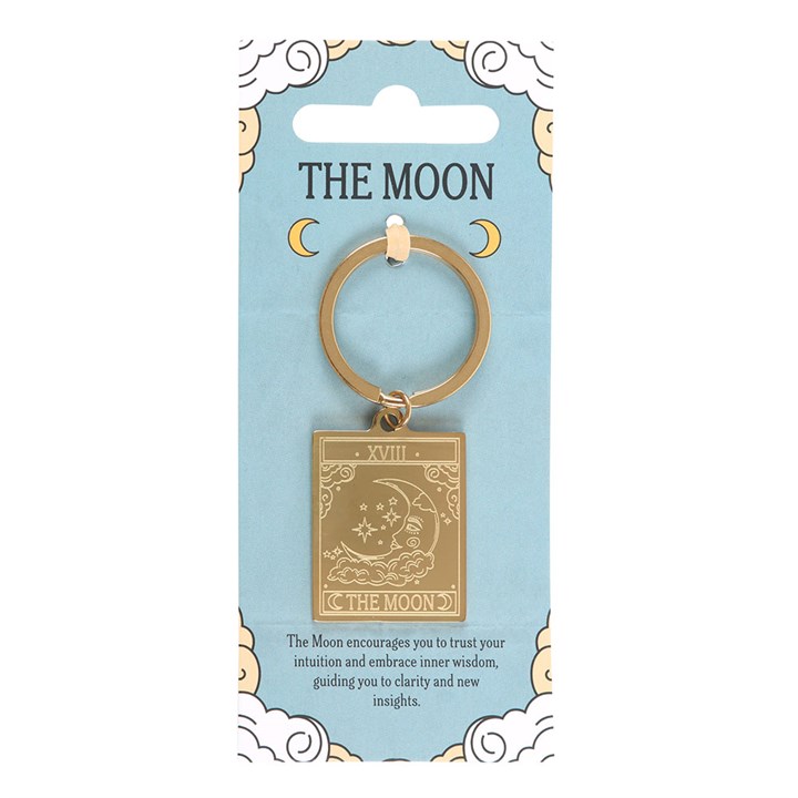 Gold 'The Moon' keychain on a blue card with celestial designs