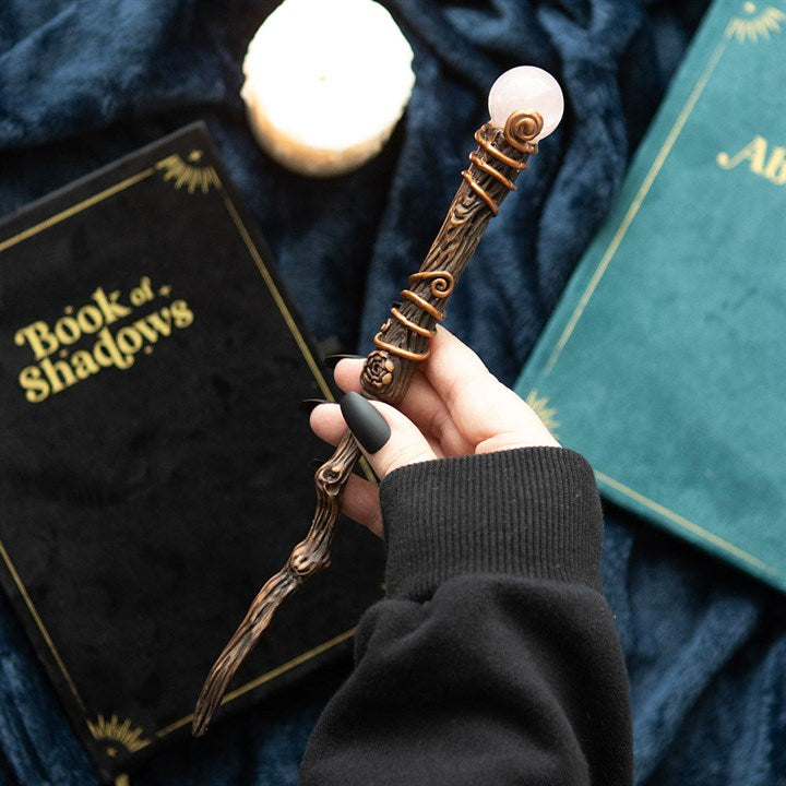 Hand holding a decorative pen with a candle and books in the background